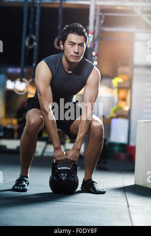 Young man training with kettlebell in crossfit gym Stock Photo