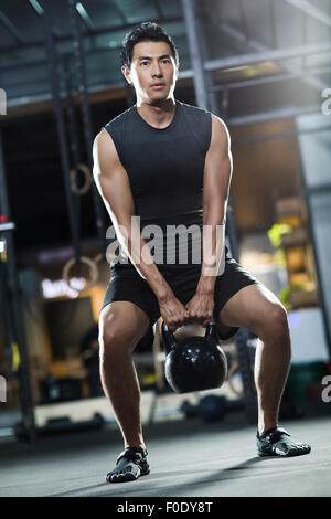 Young man training with kettlebell in crossfit gym Stock Photo