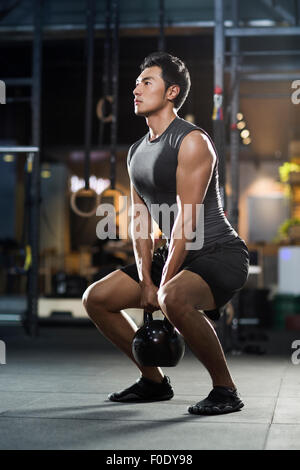 Young man training with kettlebell in crossfit gym Stock Photo