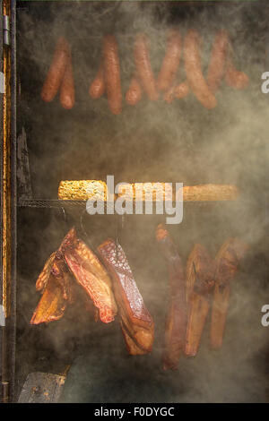 Indian corn, homemade sausages, cheese and ham in barbecue smoker. Stock Photo