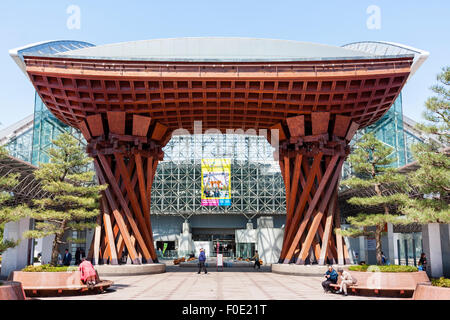 Japan, Kanazawa station. The orange Tsuzumi-mon, drum shaped gate outside the atrium, Motenashi (Welcome) glass framed Dome. Blue sky. Stock Photo