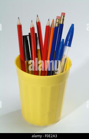 Biro pens & pencils in a yellow pot on a light background Stock Photo