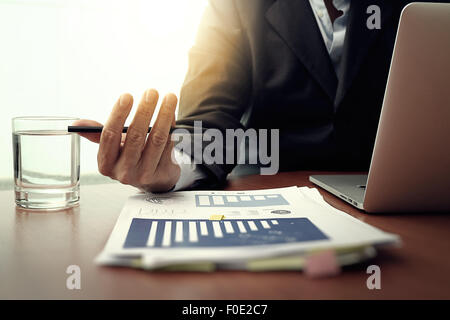 business documents on office table with smart phone and digital tablet and graph business diagram and man working in the backgro Stock Photo
