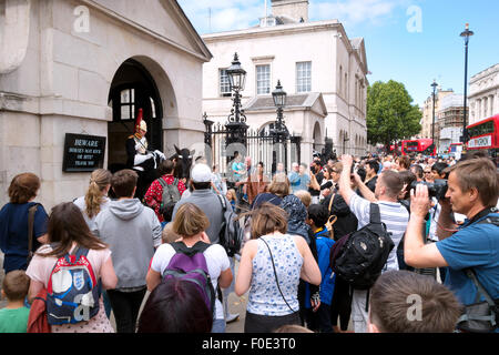 Crowd of tourists taking photos of a Horseguard, Horseguards, Whitehall, London England, UK Stock Photo