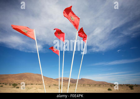 National flags of Morocco waving on flagpoles against above blue sky. Low angle view. Stock Photo