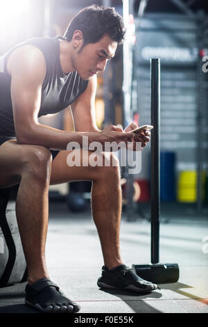 Young man using smart phone in gym Stock Photo