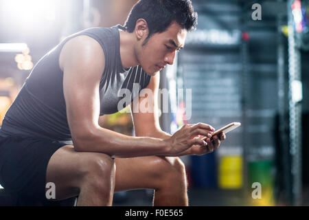 Young man using smart phone in gym Stock Photo