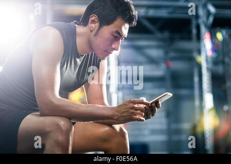 Young man using smart phone in gym Stock Photo