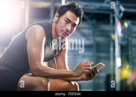 Young man using smart phone in gym Stock Photo