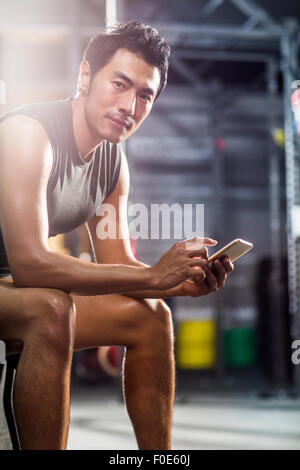 Young man using smart phone in gym Stock Photo