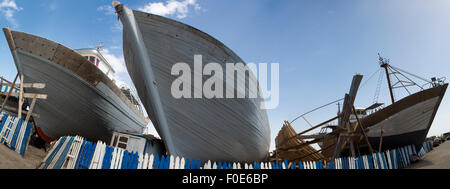 Panorama of wooden fishing boats under construction in shipyard in the harbour of Essaouira against a blue clear sky, Morocco. Stock Photo