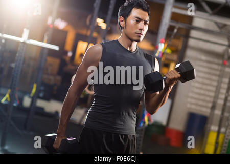 Young man lifting weights at gym Stock Photo