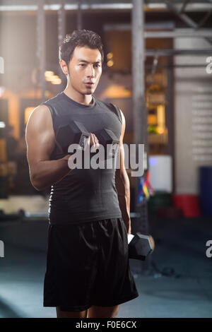 Young man lifting weights at gym Stock Photo