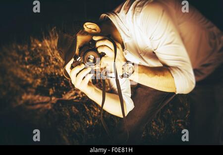 Photographer in Action. Caucasian Male Taking Pictures Using Vintage Analog Camera. Sepia Color Grading Photography Concept. Stock Photo
