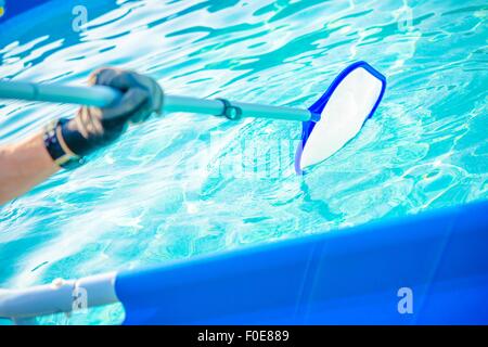 Backyard Garden Swimming Pool Cleaning Closeup. Taking Care of Pool. Stock Photo