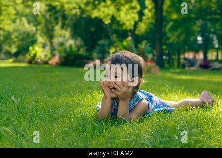 Cute little girl laying in the grass on a sunny summer day Stock Photo