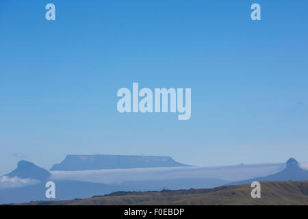 White clouds in blue sky over table-top mountains called Tepui in Gran Sabana, Guayana Highlands, Venezuela, South America. Even Stock Photo