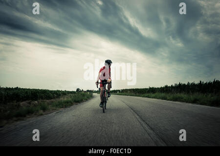 Cyclist riding on country road Stock Photo