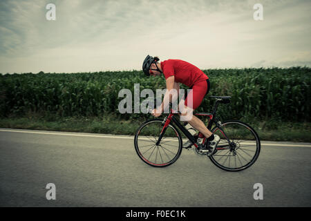 Cyclist riding on country road Stock Photo