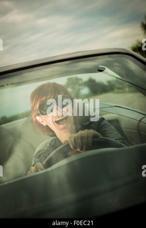 Excited woman enjoying driving her convertible car Stock Photo