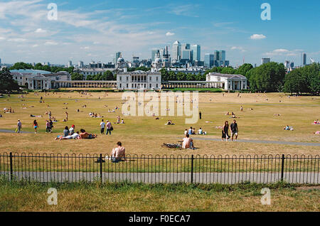 Greenwich Park, South East London,UK, in the summertime, with sunbathers and Canary Wharf in the far distance Stock Photo