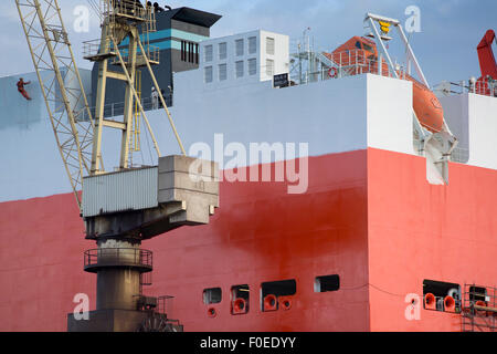 shipyard worker painting a ship under construction on drydock in Gdansk Shipyard. Stock Photo