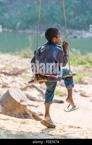 Young Orang Asil boy swinging and looking into the distance, native, Taman Negara, Malaysia Stock Photo