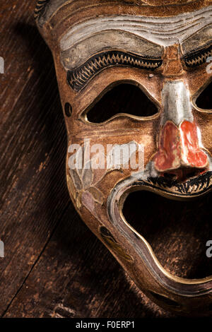 Comedy mask lying on wooden background. Still life showing happiness and positive expression through an object. Stock Photo