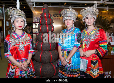 Hong Kong. 14th Aug, 2015. Ladies in traditional ethnic dress from the Wujunong Tea Company in China stand by tall tower of compressed tea bricks. Hong Kong's 7th annual Tea fair at the HKCEC brings the worlds best teas to one venue. 12 countries are represented at the fair which is a celebration of the culture and traditions of tea and features The Hong Kong Style Milk tea making Credit:  Jayne Russell/Alamy Live News Stock Photo