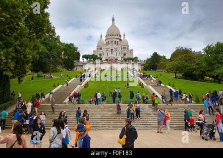PARIS, FRANCE - JULY 27, 2015: Tourists are sitting and walking in the park in front of the Sacre-Coeur in Montmartre, one of th Stock Photo