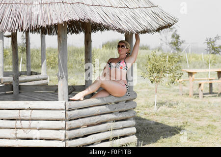 the beautiful woman sits in a wooden arbor Stock Photo