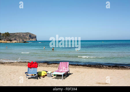 Two empty sun loungers on beach with sea in backtround Stock Photo