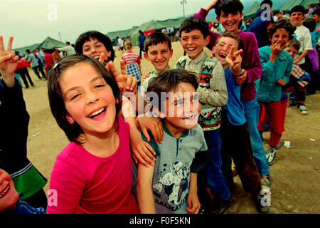 Kosovan refugees at camp Strankovic  Macedonia 1999 .. kids happy and playing whilst stood in food queues Stock Photo