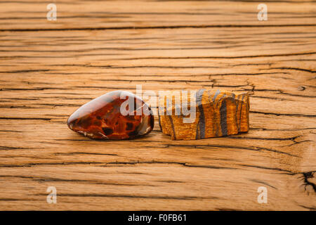 Piece of pietersite and rough tiger eye originating from Namibia Africa on wood. Pietersite metamorphic gem stone type of tiger Stock Photo