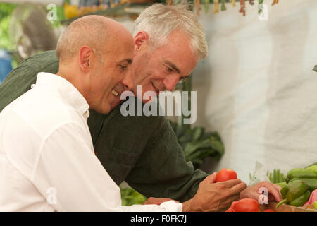 Older, senior, mature gay male couple shopping for produce at farm stand or produce stand in countryside Stock Photo