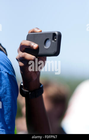 Man using smart phone to video tape an outdoor event - USA Stock Photo