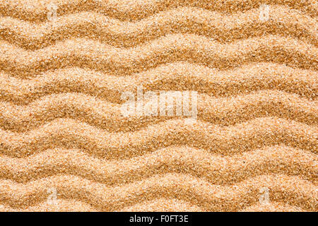 A series of wave patterns set on beach sand. This can be used as a background to denote beach, summer etc. Stock Photo