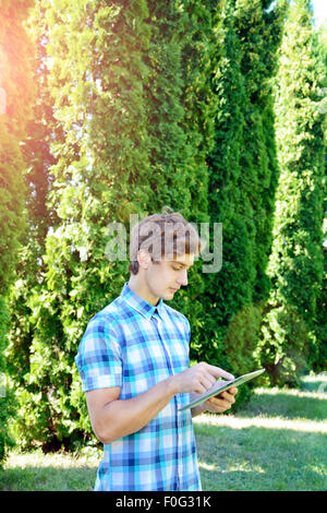 Young man is using tablet in the park Stock Photo