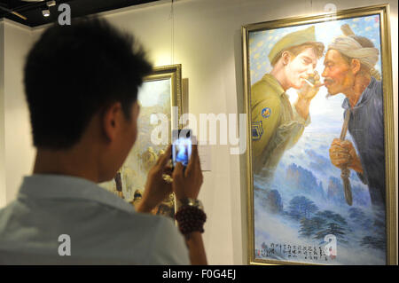 Chongqing. 15th Aug, 2015. A visitor takes photos of a painting with mobile phone at an exhibition about 'Flying Tigers' in southwest China's Chongqing, Aug. 15, 2015. A large amount of photos, paintings and personal belongings about 'Flying Tigers' were displayed at the exhibition opened on Saturday. The Flying Tigers, officially known as the American Volunteer Group of the Chinese Air Force, were formed in 1941 and led by U.S. General Claire Lee Chennault to help China drive out invading Japanese troops. Credit:  Tang Yi/Xinhua/Alamy Live News Stock Photo