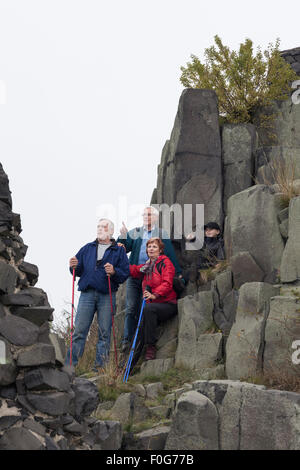 Three seniors with child boy pointing and hiking on rocky terrain. Stock Photo