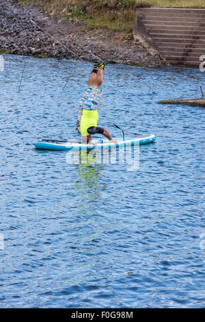 A man  doing a headstand on a paddle board at Chasewater Country Park lichfield, Staffordshire, UK Stock Photo