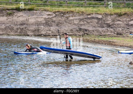 A man Giving paddle boarding lessons to a group of people at Chasewater Country Park lichfield, Staffordshire, UK Stock Photo