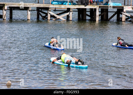 A man Giving paddle boarding lessons to a group of people at Chasewater Country Park lichfield, Staffordshire, UK Stock Photo