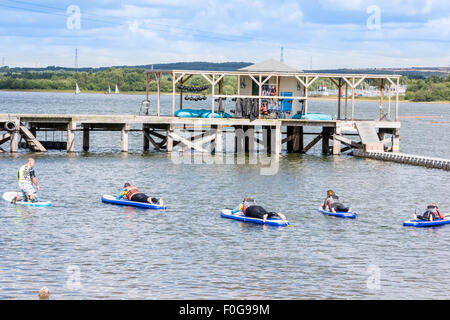 A man Giving paddle boarding lessons to a group of people at Chasewater Country Park lichfield, Staffordshire, UK Stock Photo