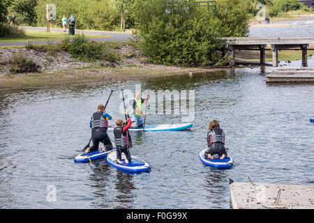 A man Giving paddle boarding lessons to a group of people at Chasewater Country Park lichfield, Staffordshire, UK Stock Photo