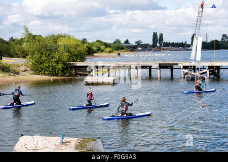 A man Giving paddle boarding lessons to a group of people at Chasewater Country Park lichfield, Staffordshire, UK Stock Photo