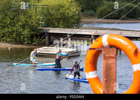 A man Giving paddle boarding lessons to a group of people at Chasewater Country Park lichfield, Staffordshire, UK Stock Photo