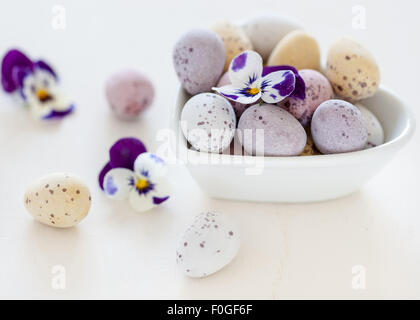 easter mini eggs and spring flowers in a heart shaped bowl Stock Photo