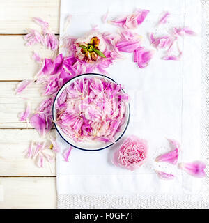 a white plate with pink peony petals on vintage white lace tablecloth Stock Photo