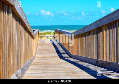 Wooden beach bridge, extending over sand dunes, towards the ocean beach. Stock Photo
